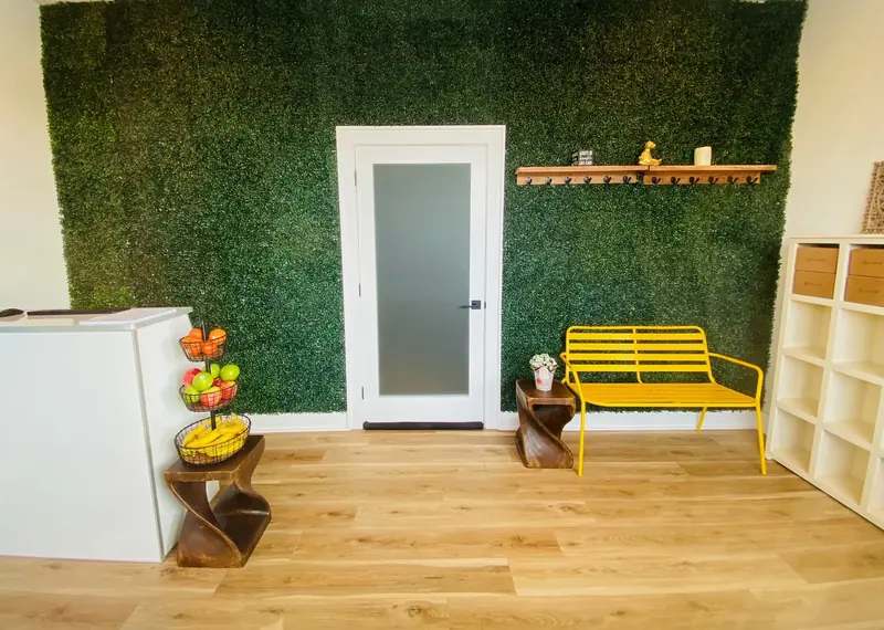 The Lotus Hot Yoga lobby, with its front desk, hedge wall and yellow bench
